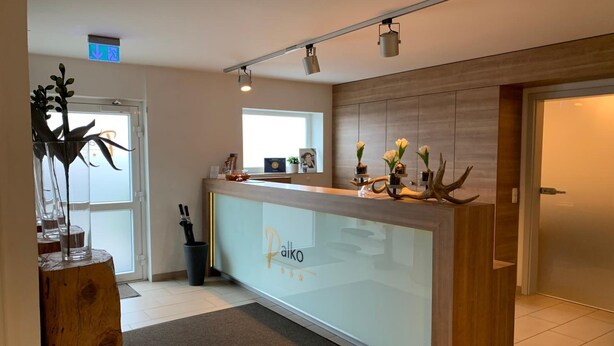 Una zona de recepción con mostrador de cristal, paneles de madera y un letrero que dice "Palko".