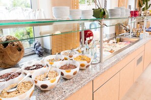 A buffet with various food items and utensils. - Hotel Bavaria Garni (Dingolfing)