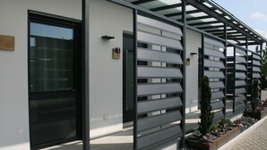 A modern building with a glass door, a metal fence, and a paved walkway. - Hotel Bavaria Garni (Dingolfing)