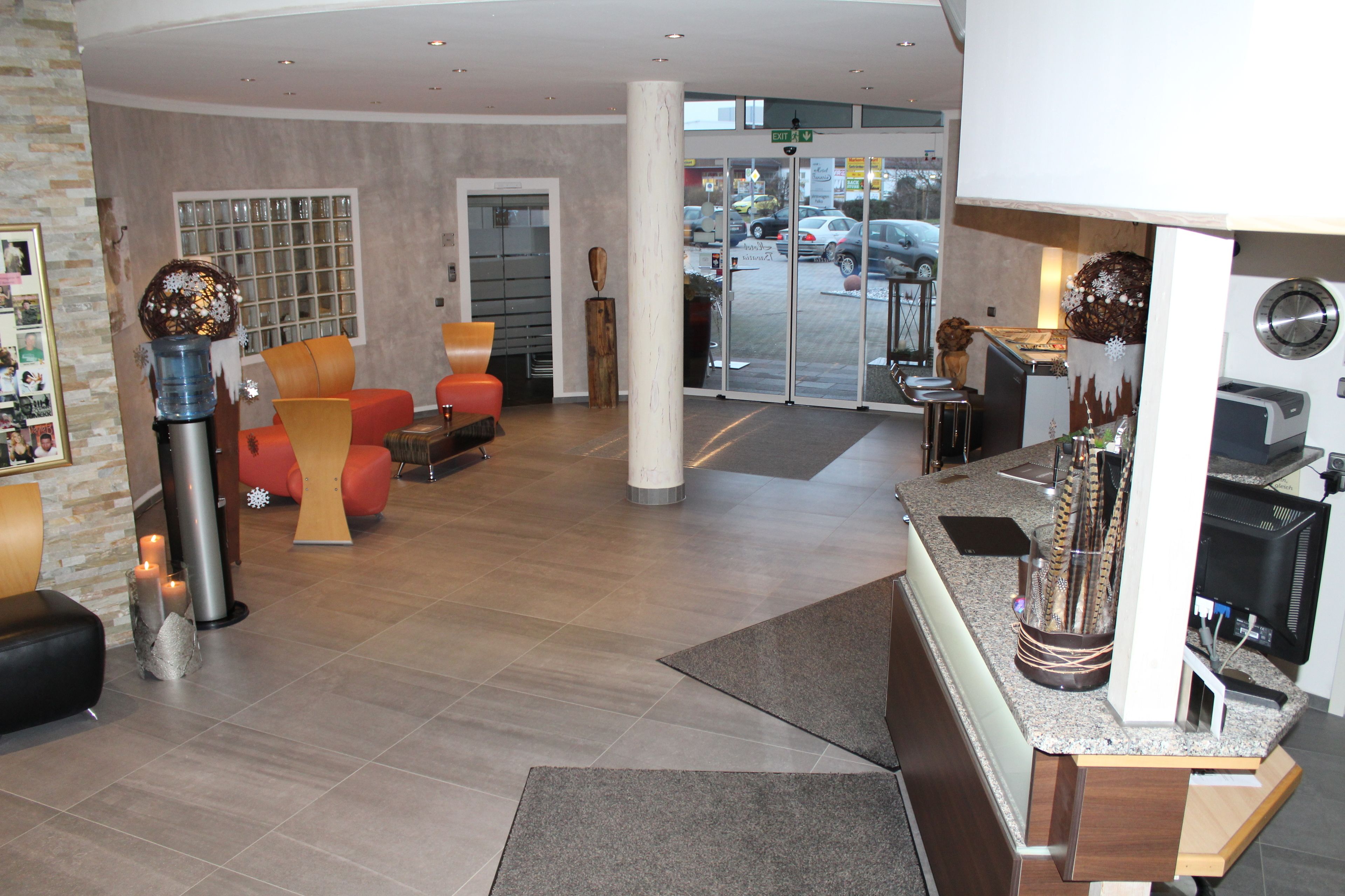 A modern lobby with a reception desk, seating area, and a glass door entrance.