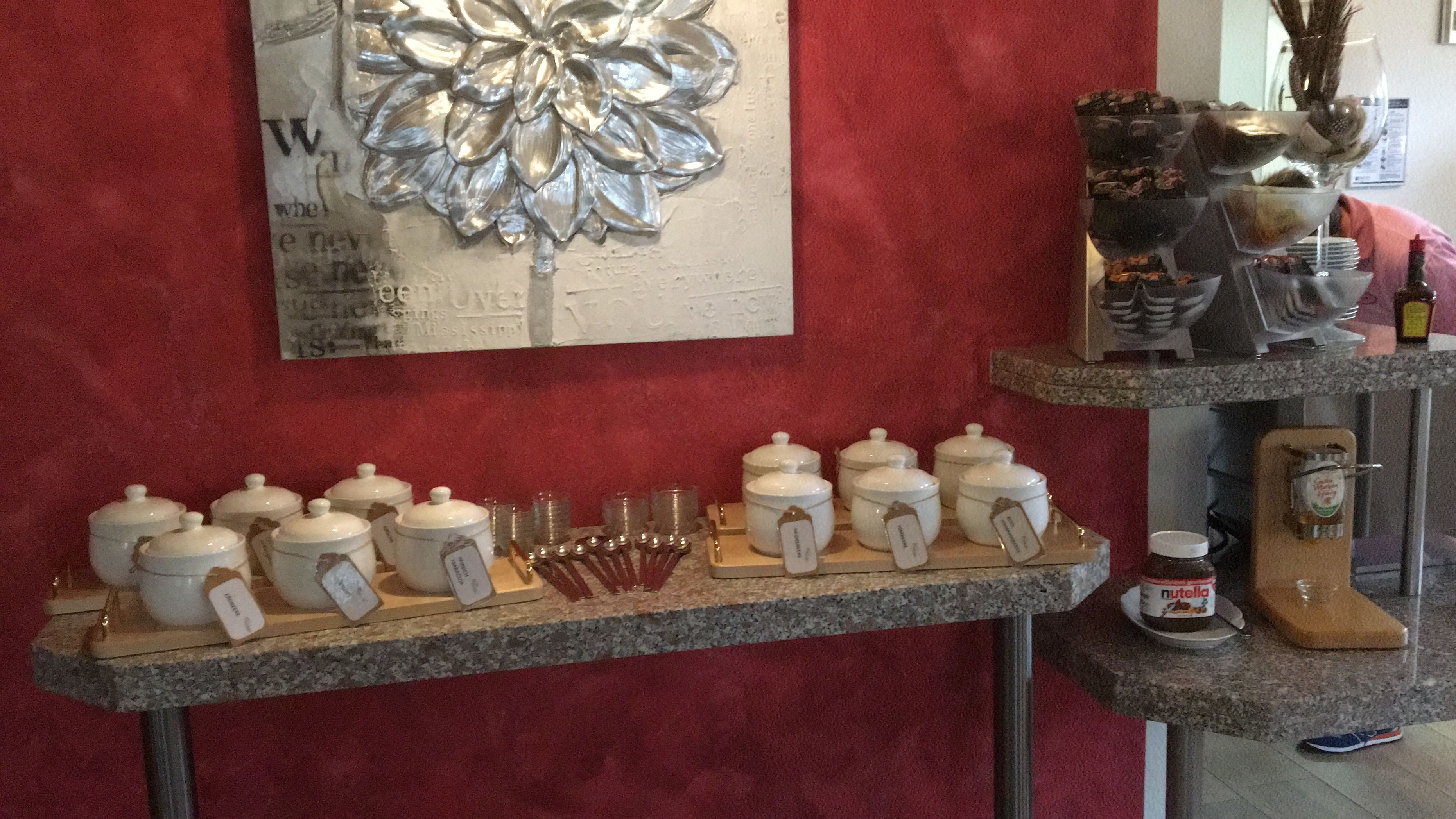 A kitchen counter with white storage jars, measuring cups, and a decorative silver flower on the wall.
