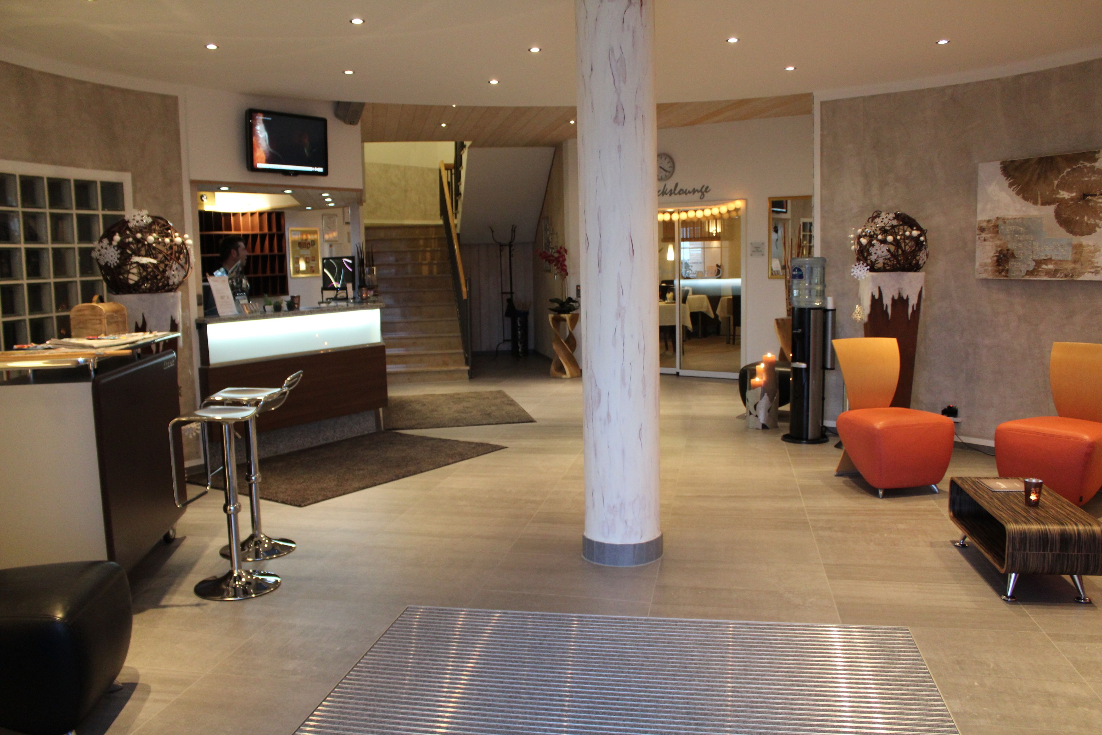 En modern entréhall med en receptionsdisk, en sittgrupp och en trappa som leder upp till de övre våningarna.