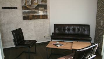 A modern living room with a leather sofa, a wooden coffee table, and a leather armchair.