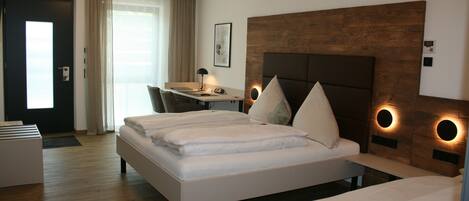 A hotel room with a large bed, a desk, and a chair.
