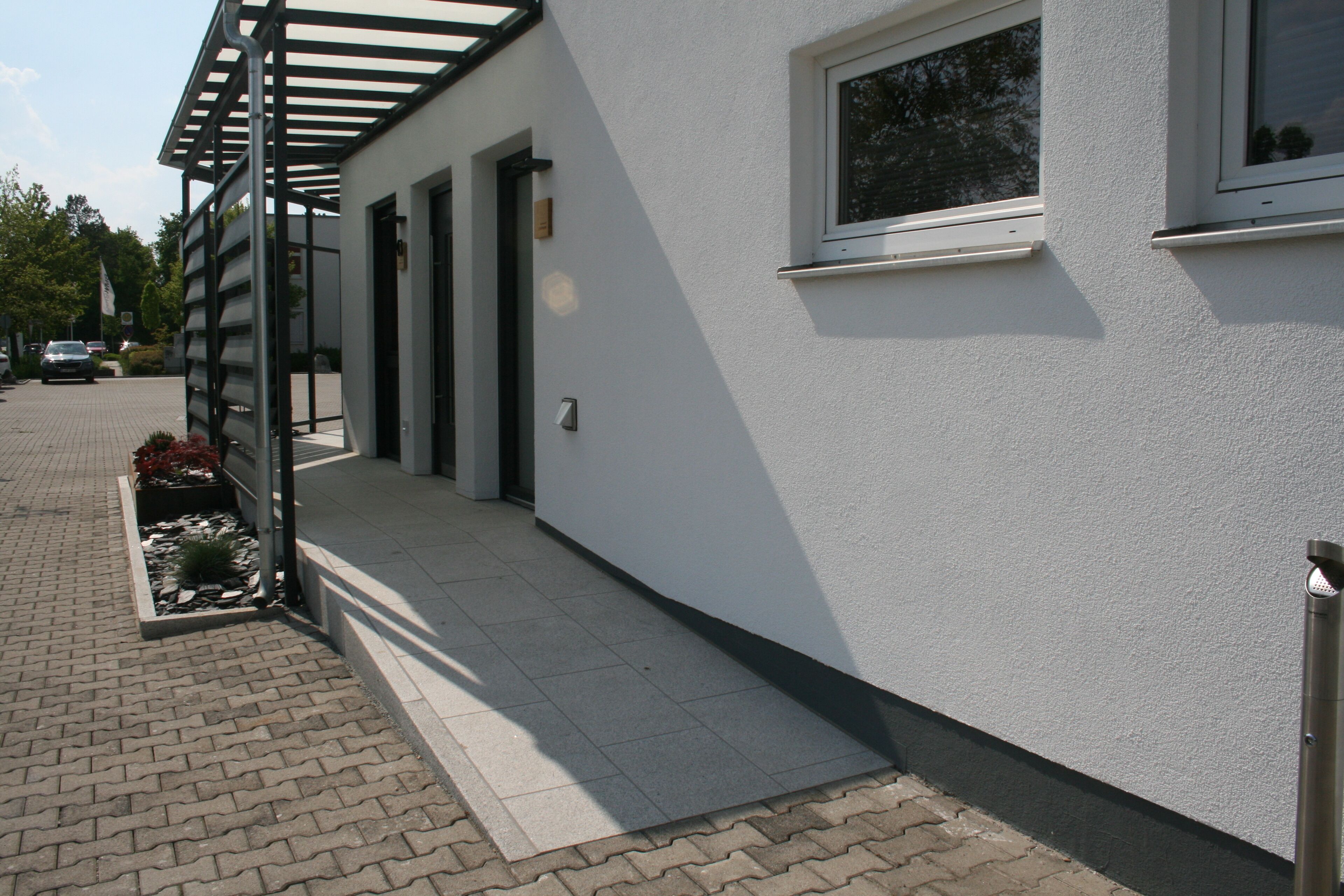 A modern building with a covered walkway, a window, and a door.