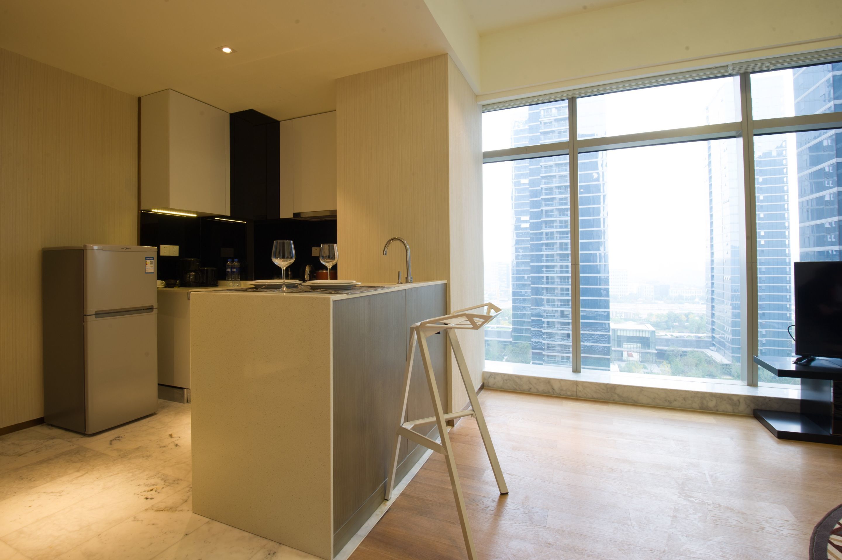 Eine moderne Küche mit einer zentralen Kochinsel, einem Einbaukühlschrank und einem großen Fenster mit Blick auf die Stadt.