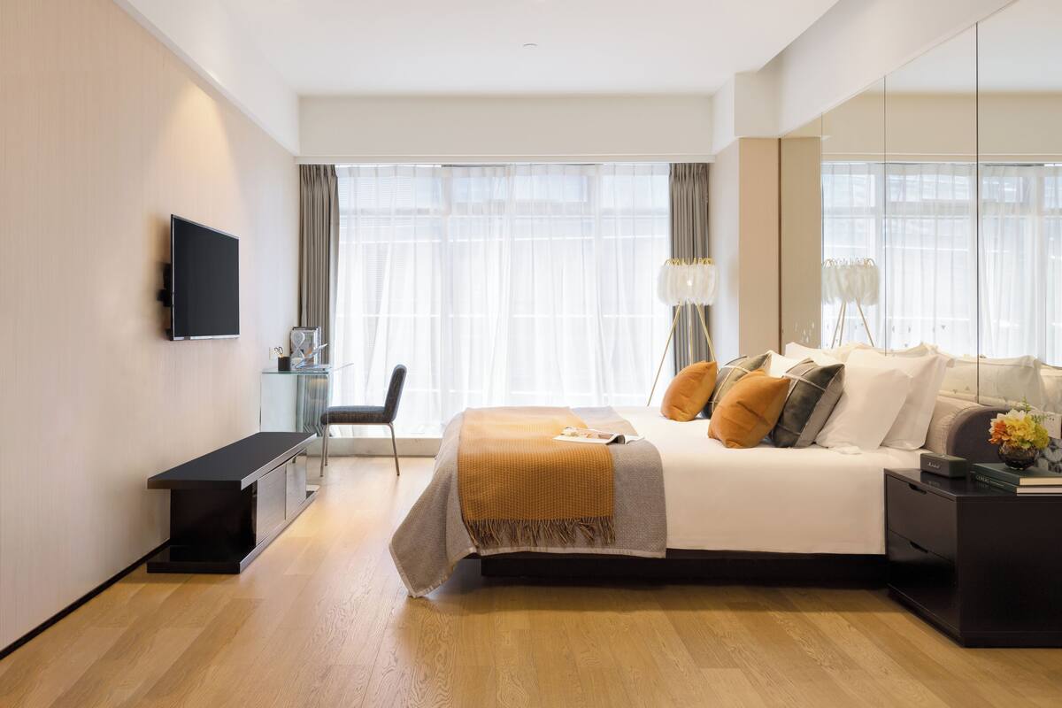 Ein modernes Hotelzimmer mit einem großen Bett, Nachttischen, einem Schreibtisch und einem Fernseher.