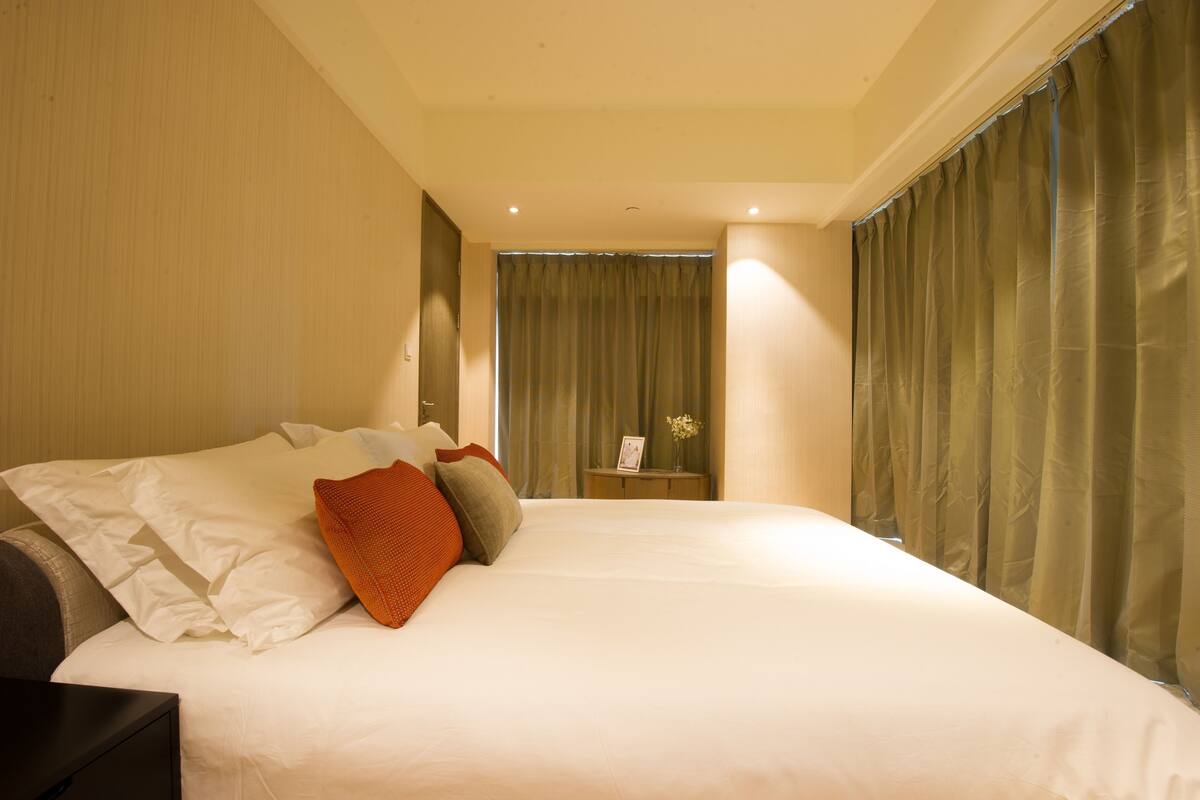 Ein Hotelzimmer mit einem großen Bett, einem Nachttisch und Blick auf den Flur.