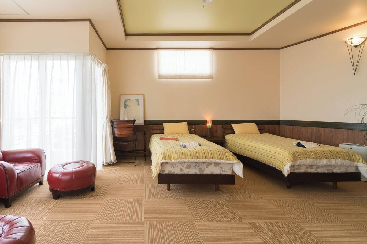 A hotel room with two beds, a sofa, a chair, and a small table.