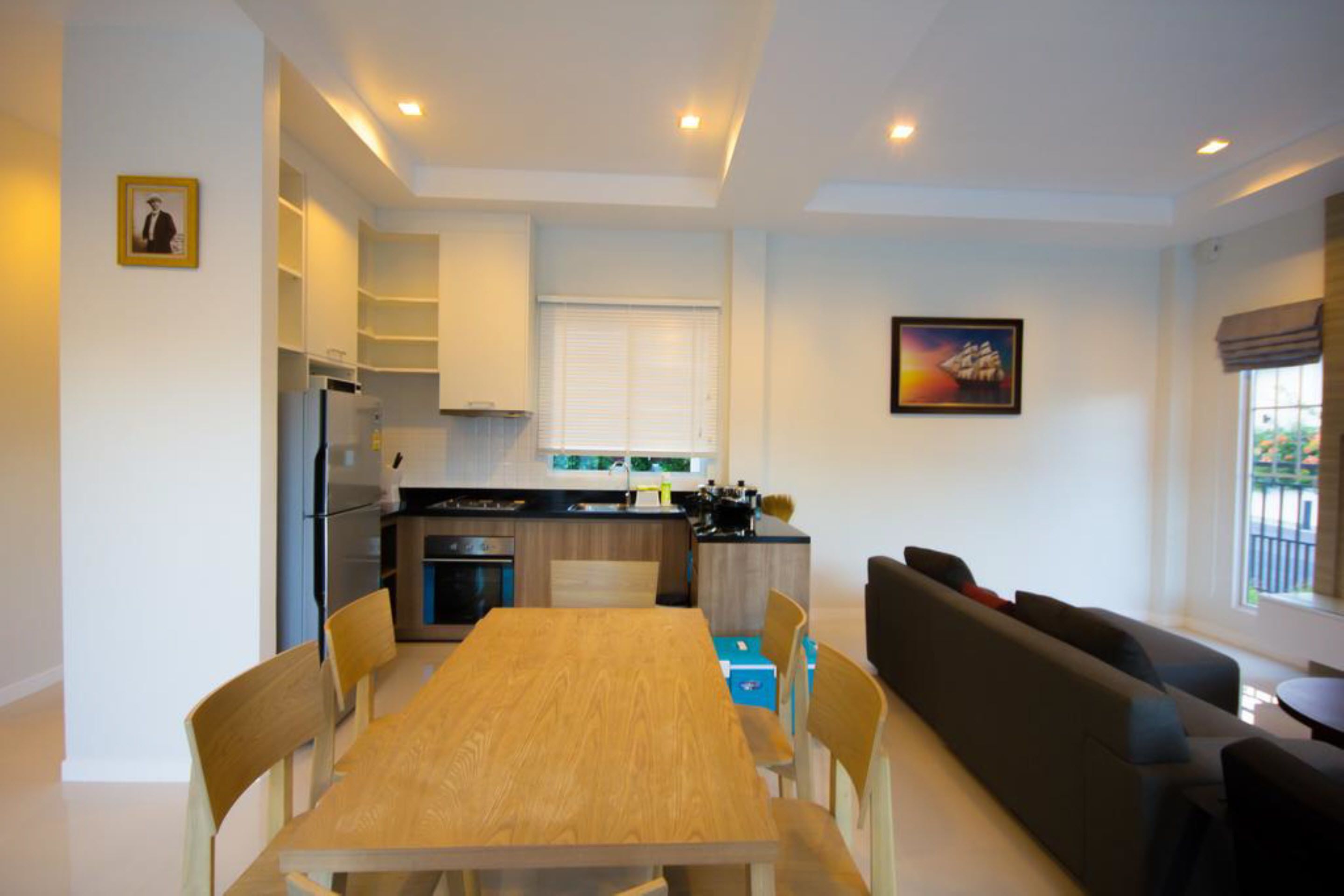 A modern kitchen with a dining table and chairs, a sofa, and a small dining table with chairs.