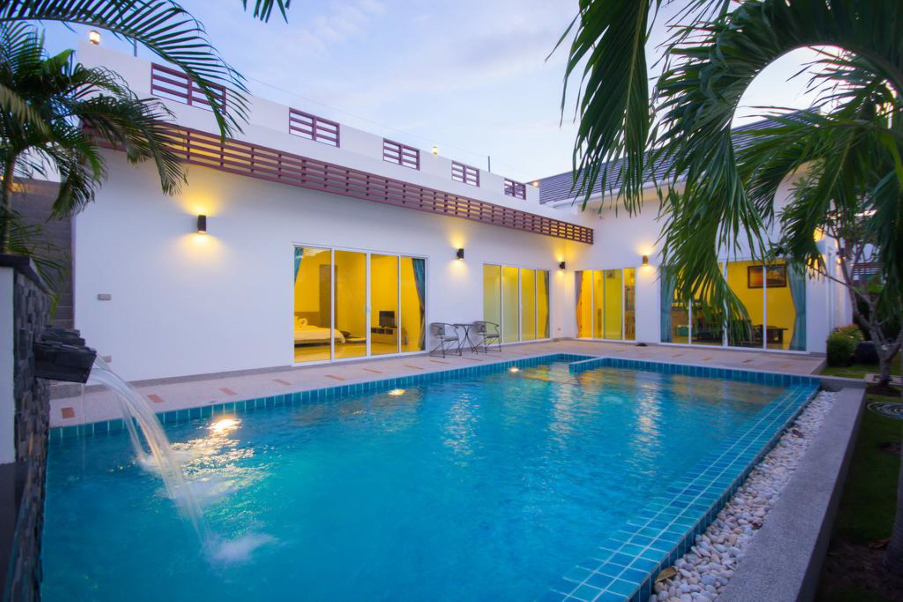 Un hotel moderno con piscina, ventanas amplias y fachada bien iluminada.