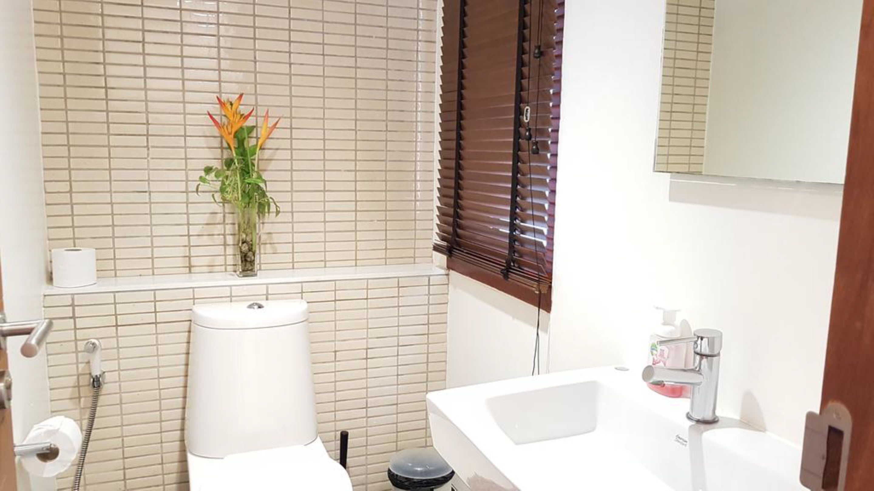 A bathroom with a toilet, sink, and window with blinds.