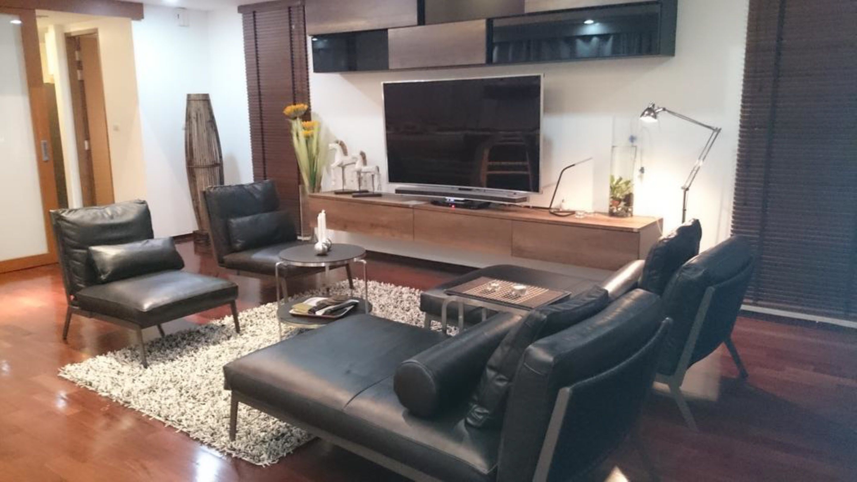 A modern living room with a leather sofa, a coffee table, a TV, and a decorative vase.