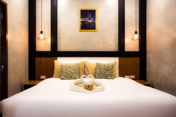 A hotel room with a large bed, two bedside tables, a framed picture on the wall, and two pendant lights. - The Sun Resort (Ratchaburi)
