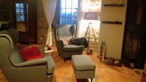 A cozy living room with a stone wall, a fireplace, a sofa, a chair, and a small table. - La Meridienne des Collines (La Motte-de-Galaure)