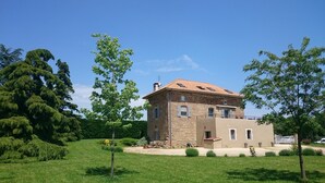 A stone building with a tiled roof, surrounded by greenery and trees. - La Meridienne des Collines (La Motte-de-Galaure)