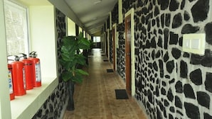 A hallway with stone walls, wooden flooring, and fire extinguishers on a shelf. - Jem Valley (Kodaikanal)