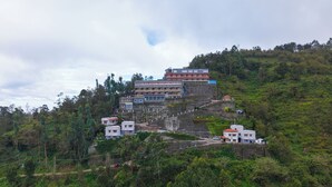 A hillside hotel with multiple buildings, including a prominent multi-story structure with balconies. - Jem Valley (Kodaikanal)
