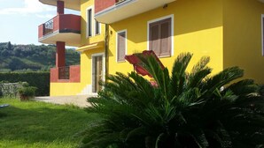 Un edifici groc amb un balcó, una porta i una finestra amb persianes.