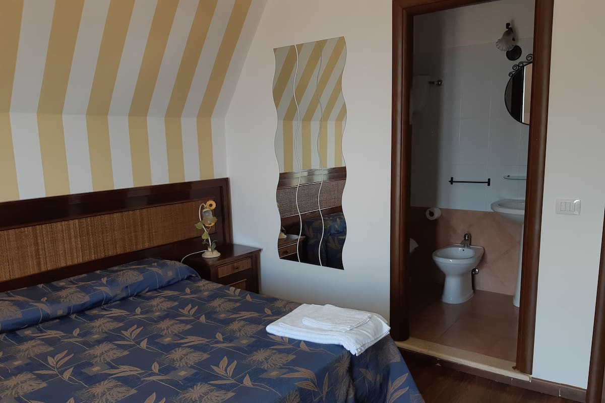 Ein Schlafzimmer mit Bett, Nachttisch und Spiegel.