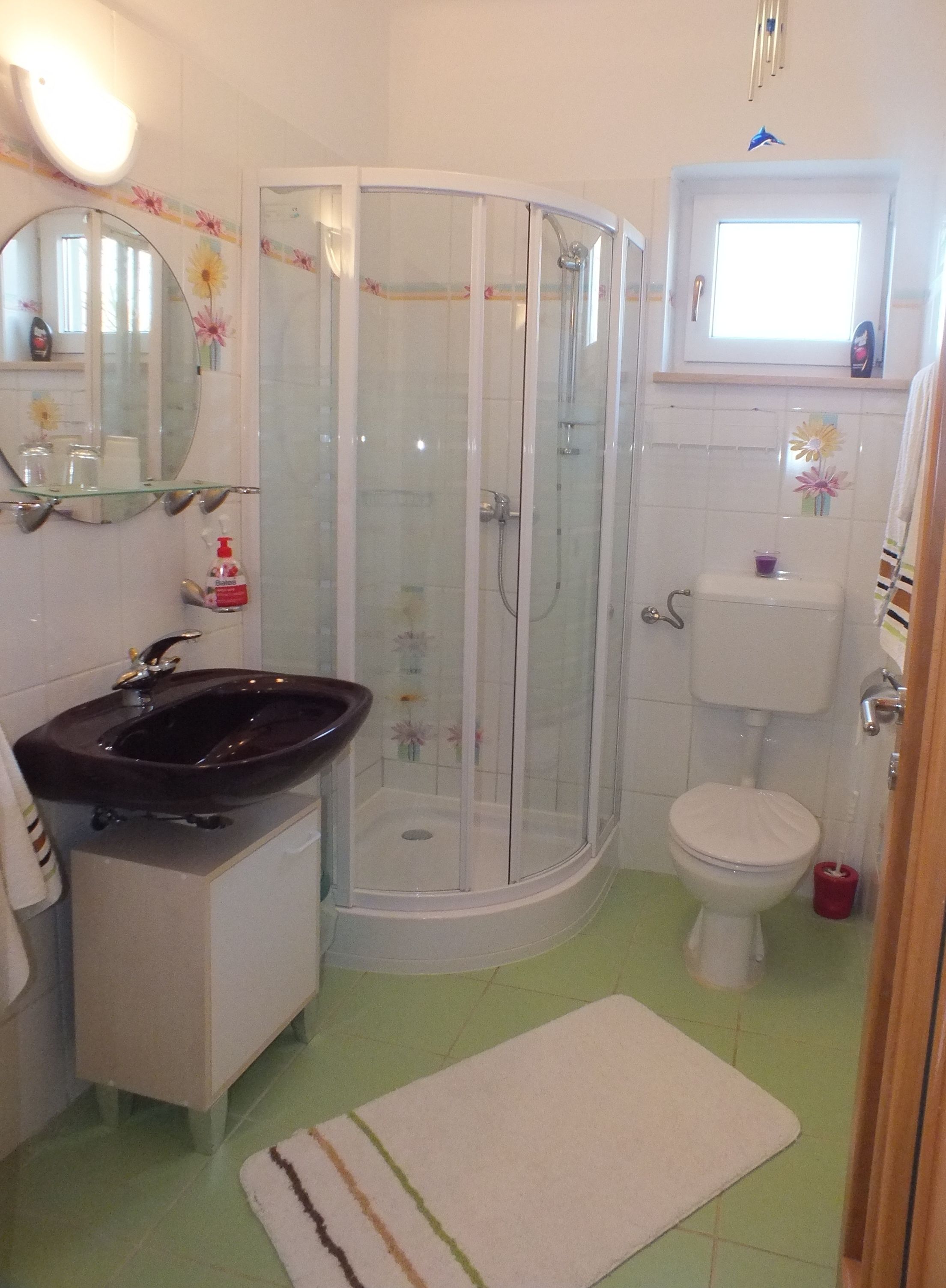 Een badkamer met een glazen douchecabine, een wastafel, een toilet en een spiegel.