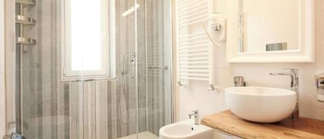 A modern bathroom with a glass-enclosed shower, a bidet, and a wooden vanity with a sink.