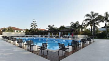 Una piscina al aire libre, sillones reclinables de piscina