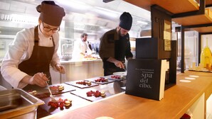 Un chef préparant des plats dans une cuisine professionnelle aux surfaces en acier inoxydable et aux éléments décoratifs en bois.