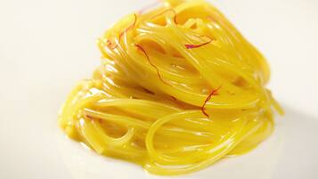 A plate of yellow pasta with red accents.