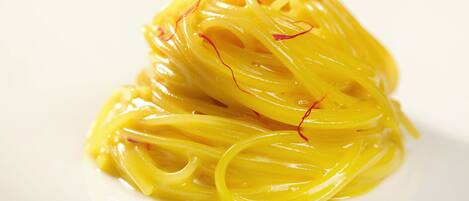 A plate of yellow pasta with red accents.