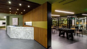 Un espace d’accueil moderne avec un comptoir en marbre, des panneaux en bois et une table de baby-foot.