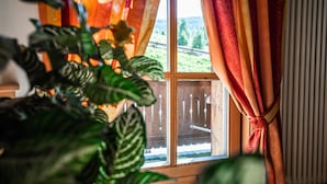 A window with a view of a wooden deck and a mountain landscape. - Chalet Mottolino (Livigno)