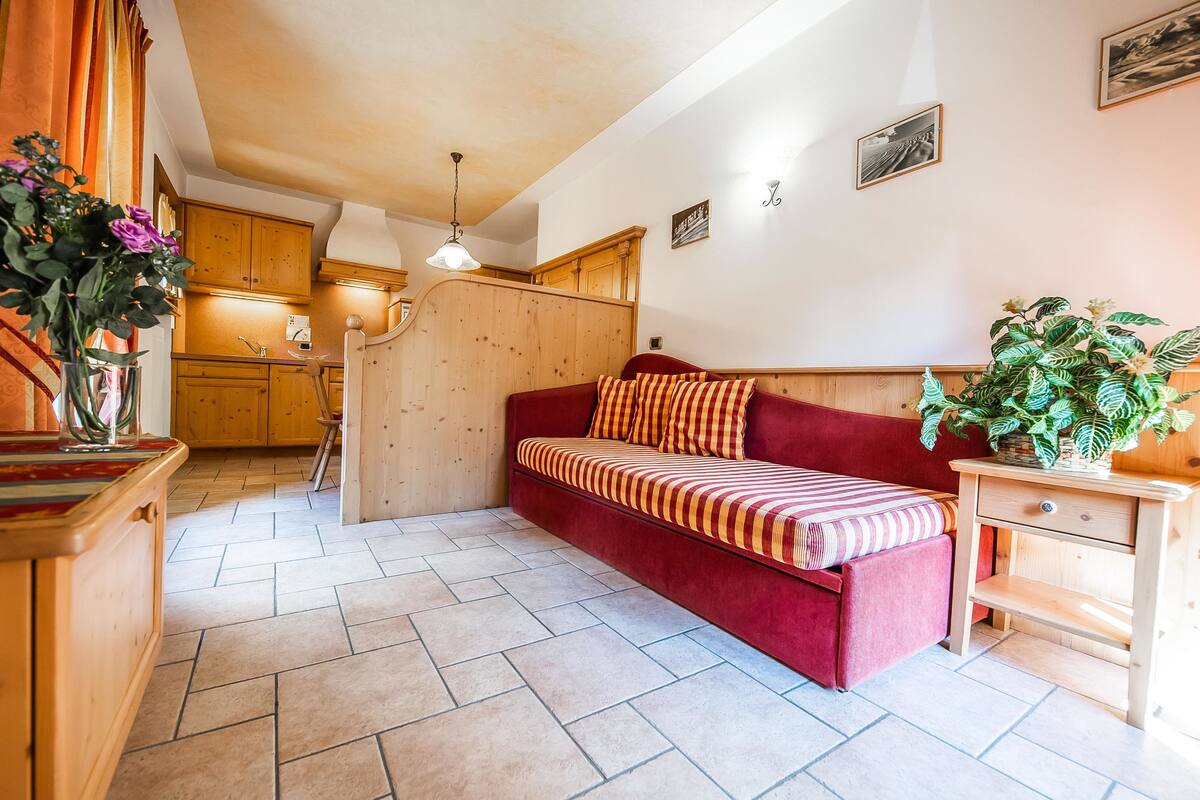 Una habitación acogedora con un sofá rojo, muebles de madera y una planta en maceta.