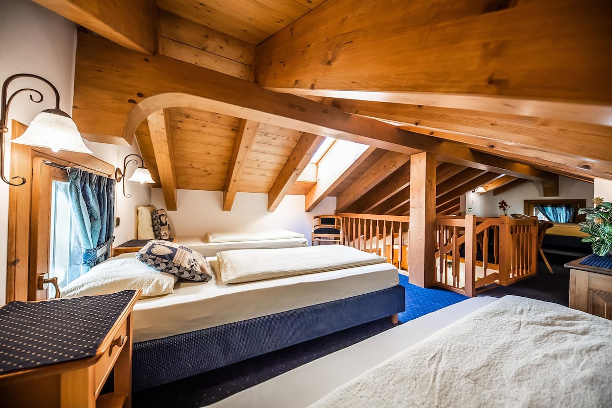 Un dormitorio acogedor en el ático con techo de madera, una cama con almohadas, un escritorio y una silla.