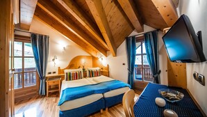 A wooden cabin room with a bed, a desk, and a TV. - Chalet Mottolino (Livigno)