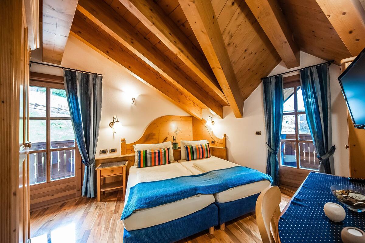 Una habitación de cabaña de madera con una cama, un escritorio y un televisor.