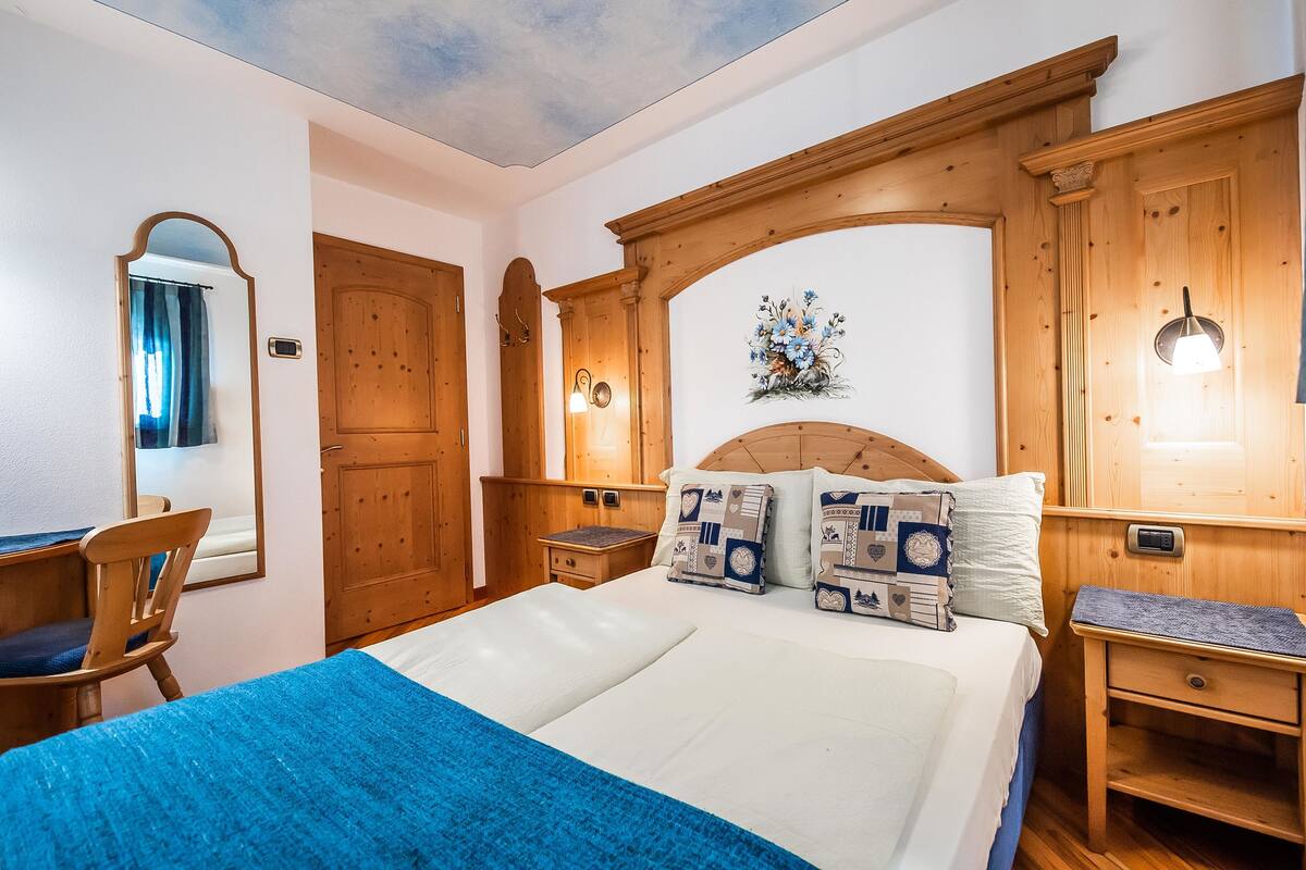 Un dormitorio con cama, armario de madera, escritorio y silla.