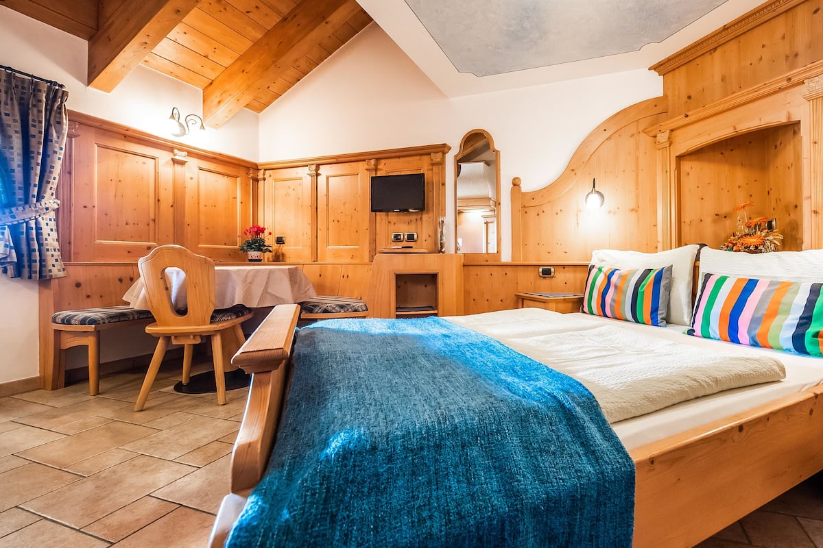 Una habitación de madera con una cama, un escritorio y una silla.