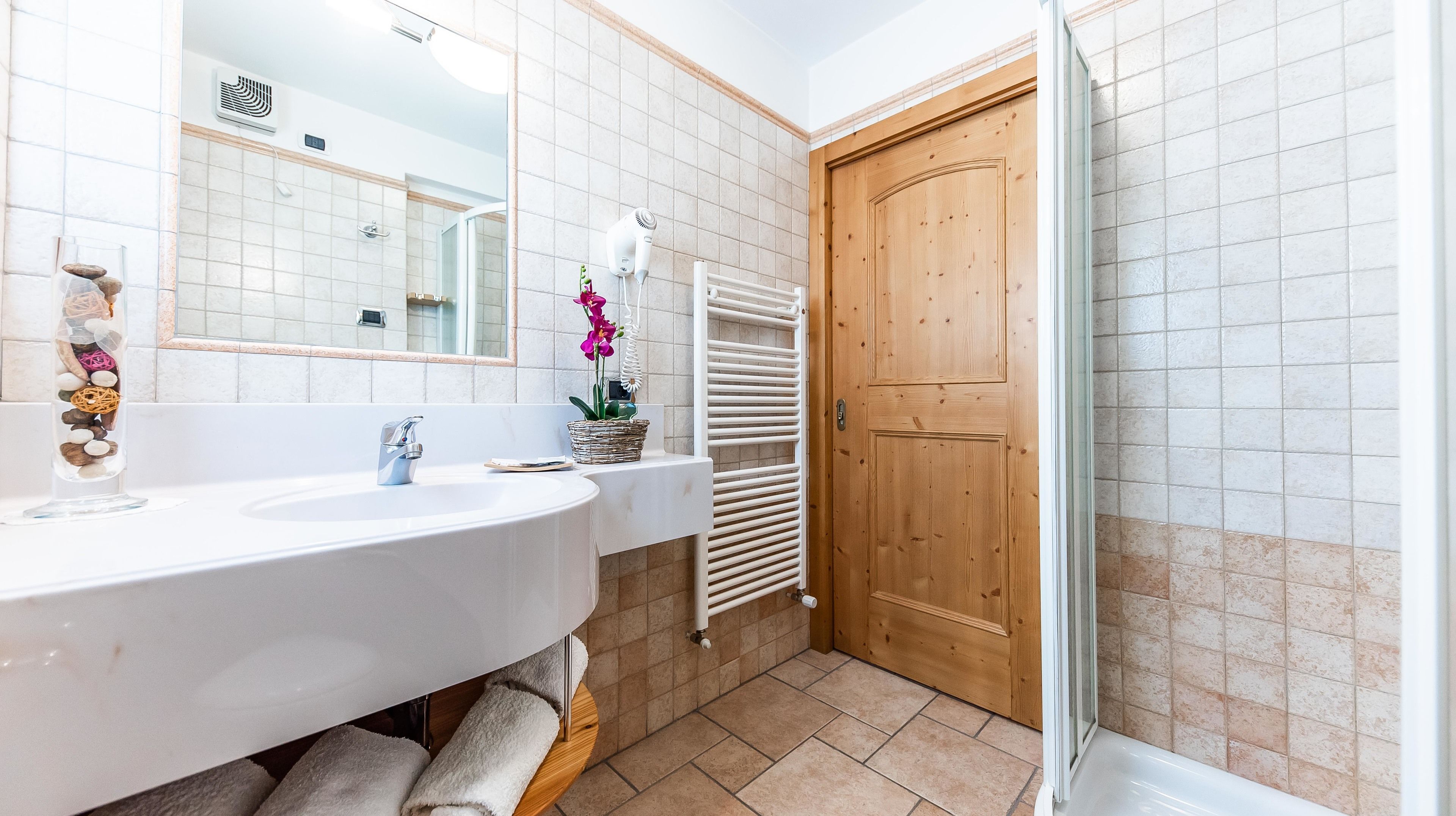 Une salle de bain avec un lavabo blanc, une porte en bois et une cabine de douche en verre.
