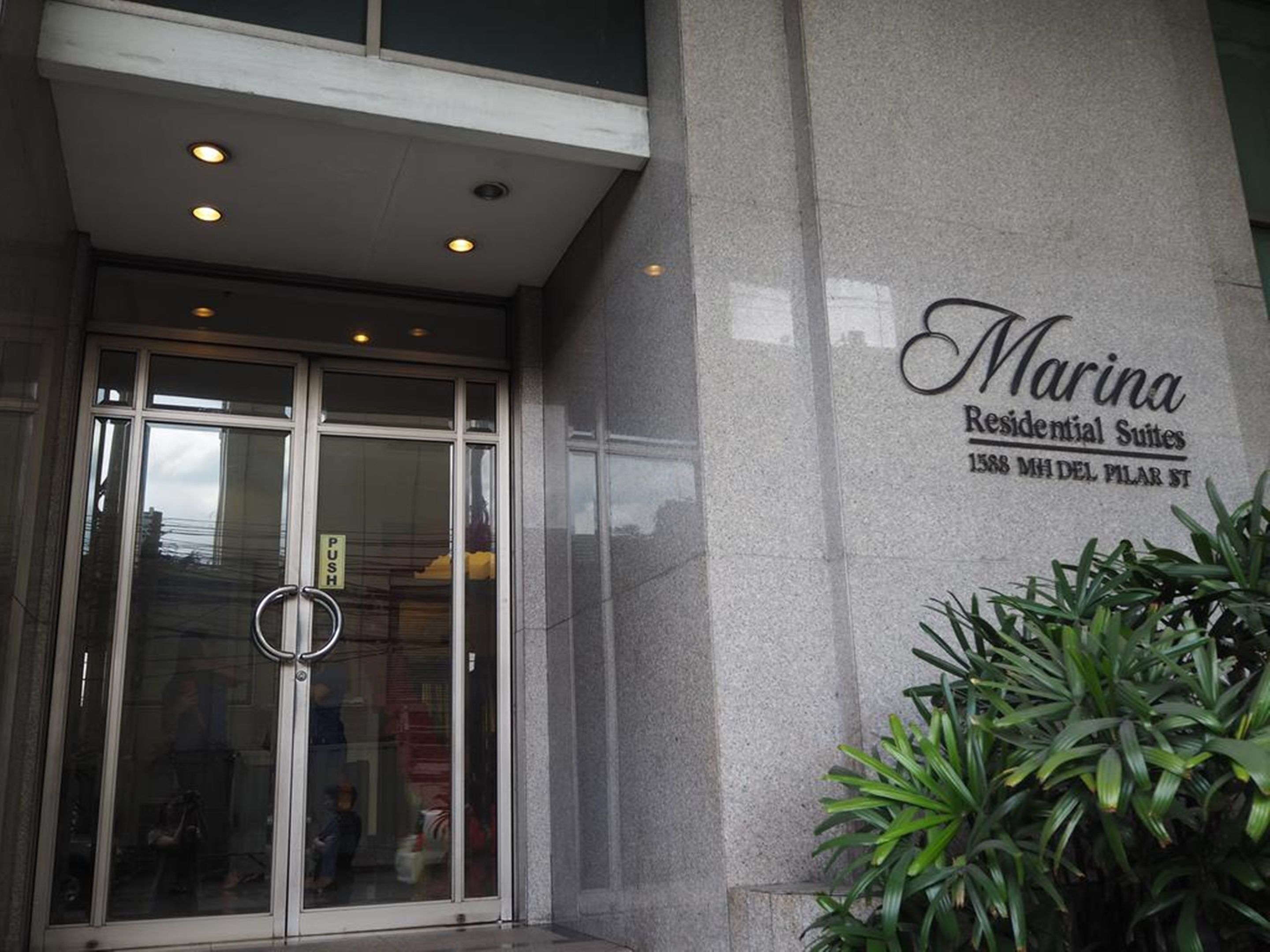 Der Eingang zum Marina Residential Suites mit Glastür, Schieber und einem Schild mit der Suitennummer.