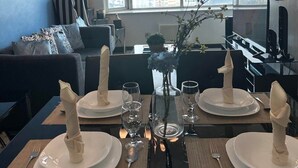 A dining area with a table set for four, a chandelier, and a view of the city through large windows. - Suites de Marina Manila (Manila)