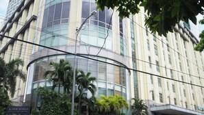 A modern building with a curved glass facade, palm trees, and a sign for the AC New World Manila Bay Hotel. - Suites de Marina Manila (Manila)