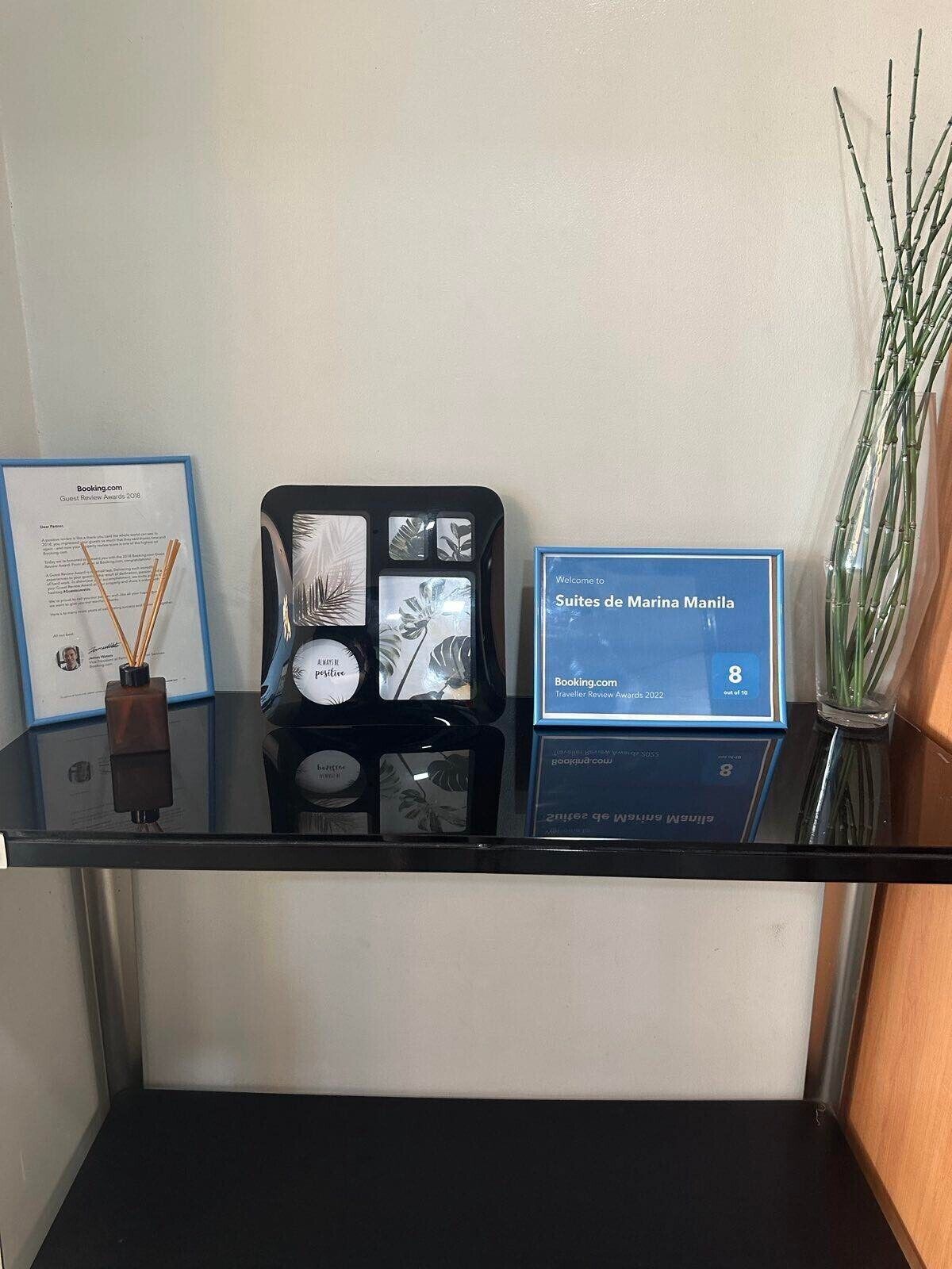 A glass display case with a framed certificate, a decorative item, and a welcome sign for Suites de Marina Manila.