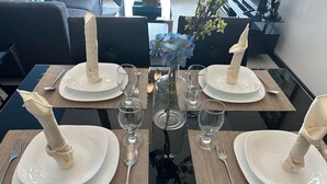 A dining table set with white plates, silverware, and clear glassware, with a vase of blue flowers in the center. - Suites de Marina Manila (Manila)