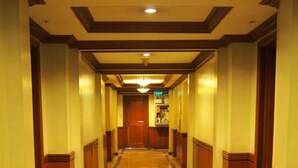 A long, narrow hallway with a polished floor and wooden paneling on the walls. - Suites de Marina Manila (Manila)