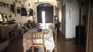 A dining area with a table set for two, surrounded by chairs, a chandelier, and various kitchen utensils and decorations on the walls. - La Posá (La Nava de Santiago)