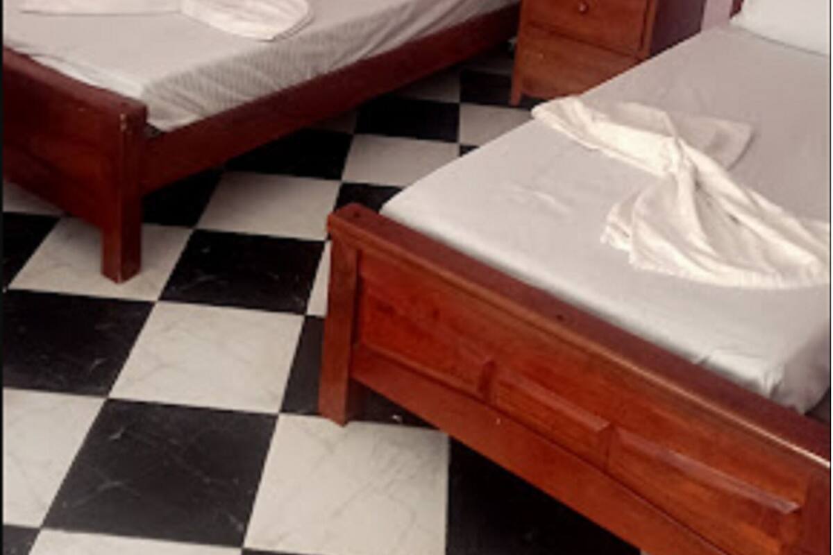 A room with two wooden beds, a nightstand, and a checkered floor.