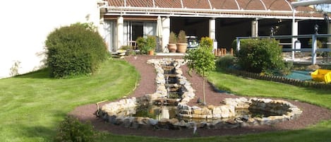 A hotel restaurant with a garden featuring a small waterfall and stone pathway.