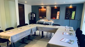 A conference room with long tables, chairs, and a coffee machine. - Relais des Lilas (Parthenay)