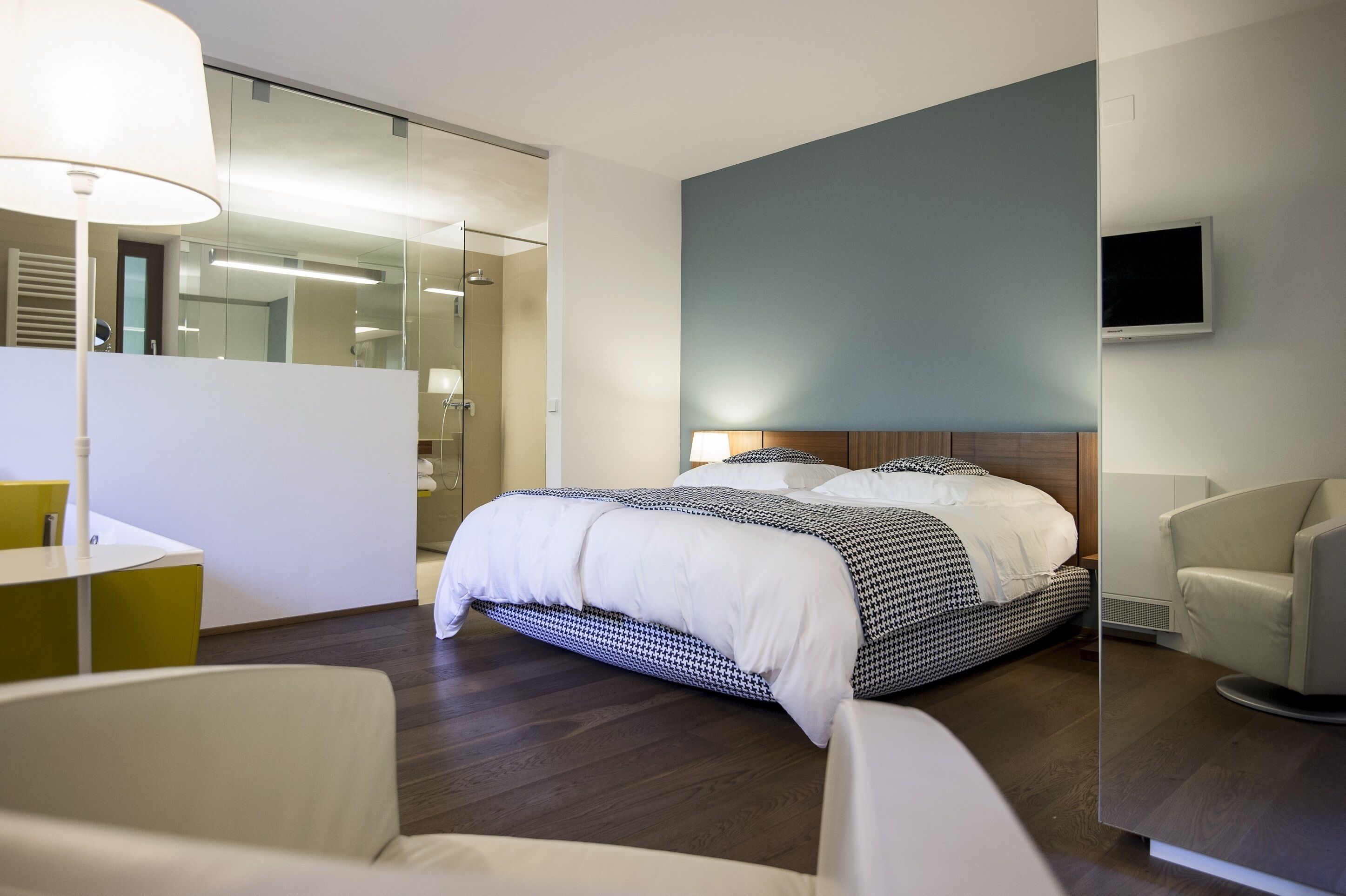 A modern hotel room with a large bed, a desk, and a chair.